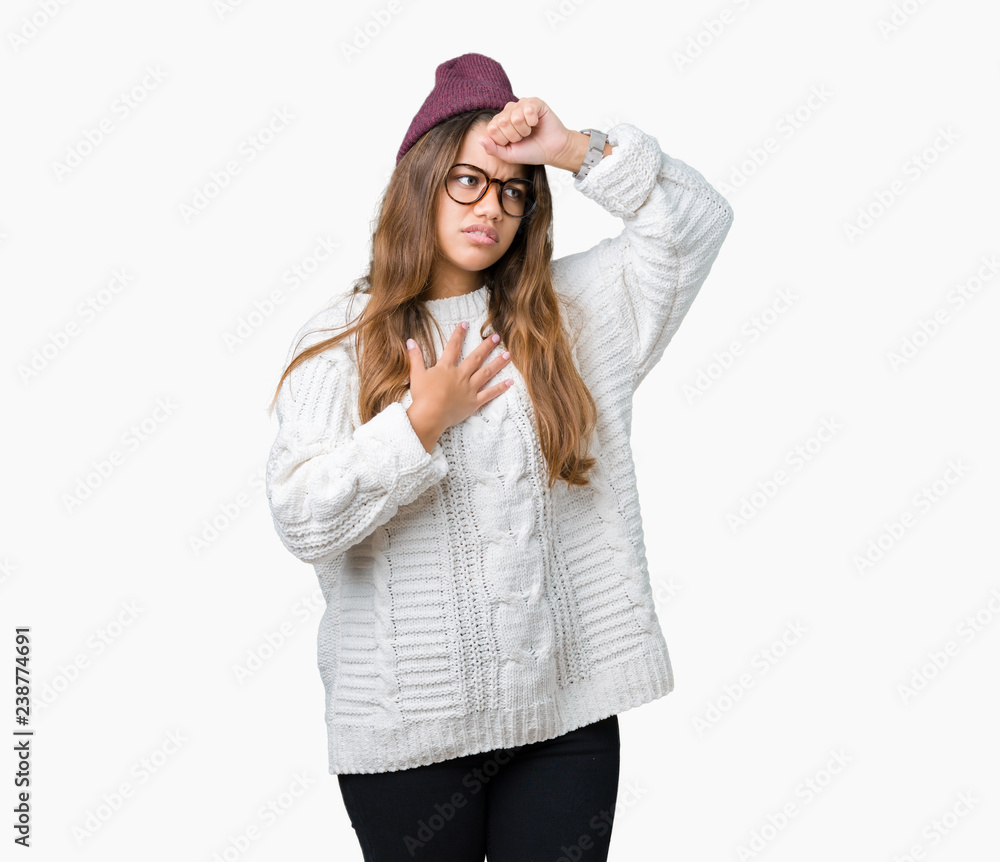 Young beautiful brunette hipster woman wearing glasses and winter hat over isolated background Touching forehead for illness and fever, flu and cold, virus sick Young beautiful brunette hipster woman wearing glasses and winter hat over isolated background Touching forehead for illness and fever, flu and cold, virus sick
