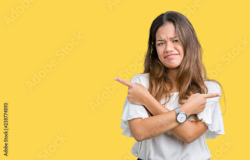 Young beautiful brunette business woman over isolated background Pointing to both sides with fingers, different direction disagree