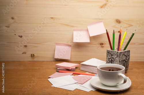 Stand for pencils, stickers, pencils and a cup of tea on a wooden background.