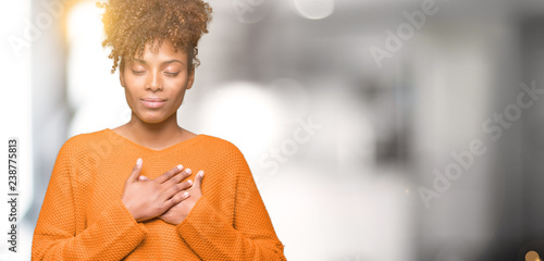 Beautiful young african american woman over isolated background smiling with hands on chest with closed eyes and grateful gesture on face. Health concept. photo