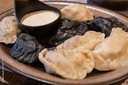 Traditional polish dumplings perogi on a plate accompanied with a white garlic sauce