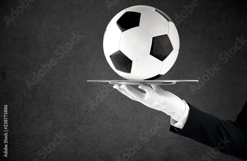 Fototapeta Naklejka Na Ścianę i Meble -  Waiter that holds a tray with soccer ball. Concept of first class service on soccer