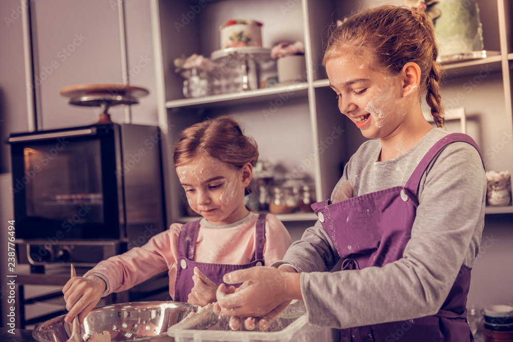 Positive young girls cooking together in the kitchen