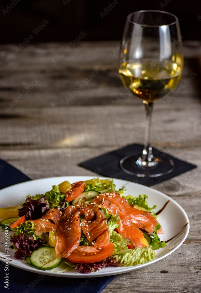 Vegetable and fresh fish salad served on a vintage table. Dinner with wine.