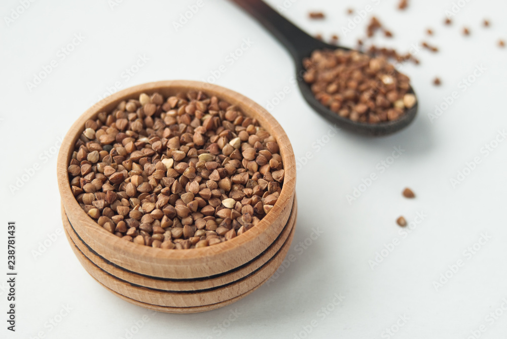 buckwheat seeds in wooden bowl and spoon. isolated on white buckwheat seeds in wooden bowl and spoon. isolated on white