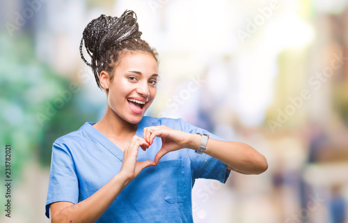 Young braided hair african american girl professional nurse over isolated background smiling in love showing heart symbol and shape with hands. Romantic concept.