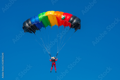 Skydiver with parachute colored in LGBT flag colors. Copy space area