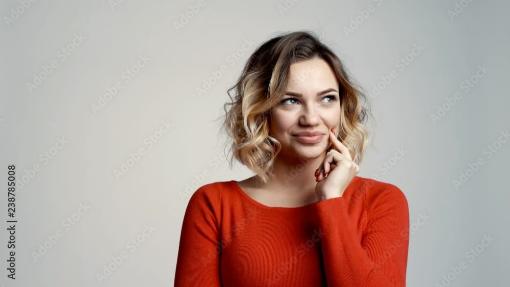 Playful beautiful young female looking mysteriously asides and gesturing finger on lips Playful beautiful young female looking mysteriously asides and gesturing finger on lips