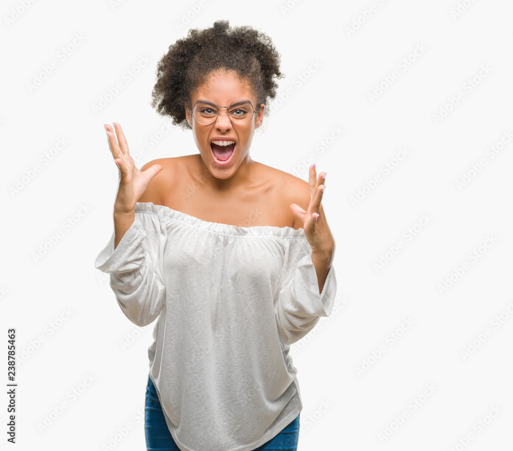Young afro american woman wearing glasses over isolated background crazy and mad shouting and yelling with aggressive expression and arms raised. Frustration concept. Young afro american woman wearing glasses over isolated background crazy and mad shouting and yelling with aggressive expression and arms raised. Frustration concept.