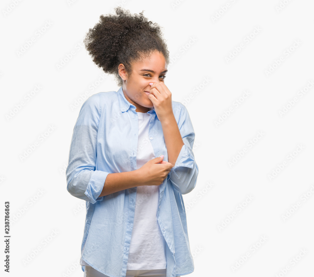 Young afro american woman over isolated background smelling something stinky and disgusting, intolerable smell, holding breath with fingers on nose. Bad smells concept. Young afro american woman over isolated background smelling something stinky and disgusting, intolerable smell, holding breath with fingers on nose. Bad smells concept.