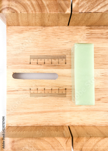 Adjustable wooden soap cutting tool from the top view with soap bar inside on the white background