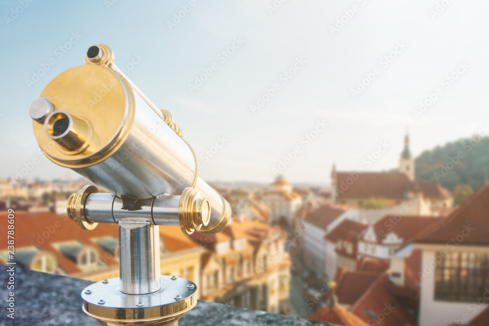Binoculars on the viewpoint. Beautiful aerial view of the traditional old or medieval architecture in Prague in the Czech Republic is blurry ahead.