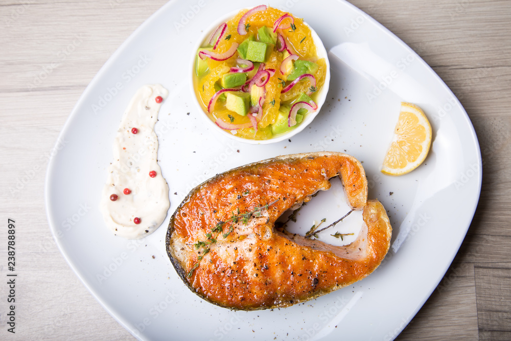 Grilled salmon, salad with oranges and avocado. Close-up, selective focus. Grilled salmon, salad with oranges and avocado. Close-up, selective focus.