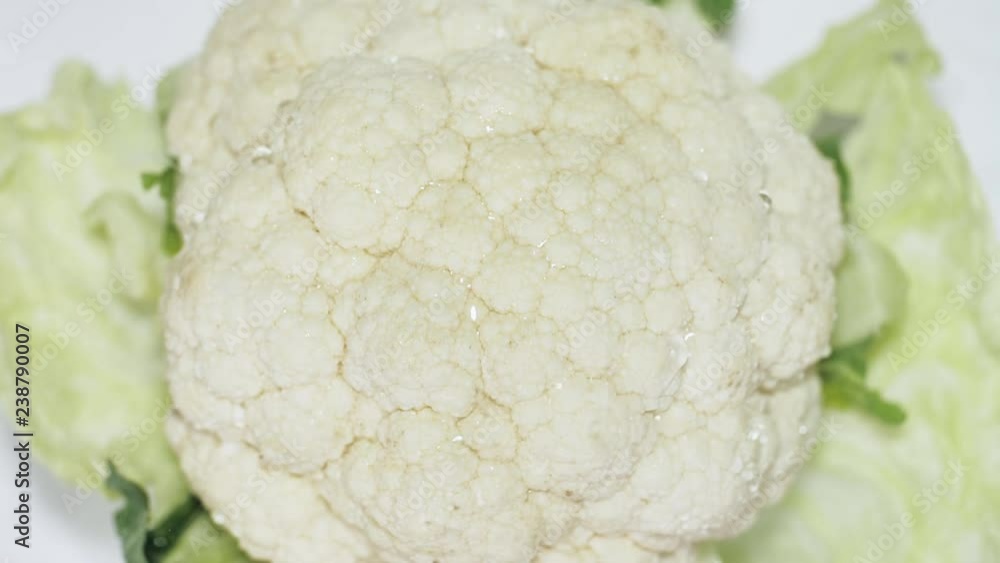 Drops of water splash on fresh white cauliflower with green leaves Drops of water splash on fresh white cauliflower with green leaves