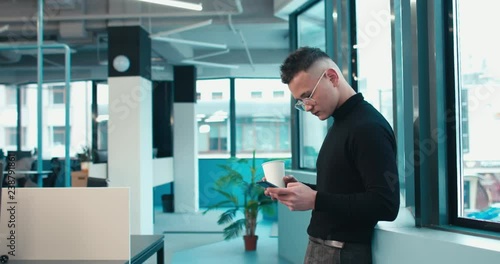 Wallpaper Mural Half length portrait of young adult middle eastern male using his phone in office during coffee break. 4K UHD Torontodigital.ca
