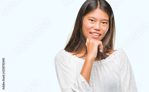 Young asian woman over isolated background looking confident at the camera with smile with crossed arms and hand raised on chin. Thinking positive. © Krakenimages.com
