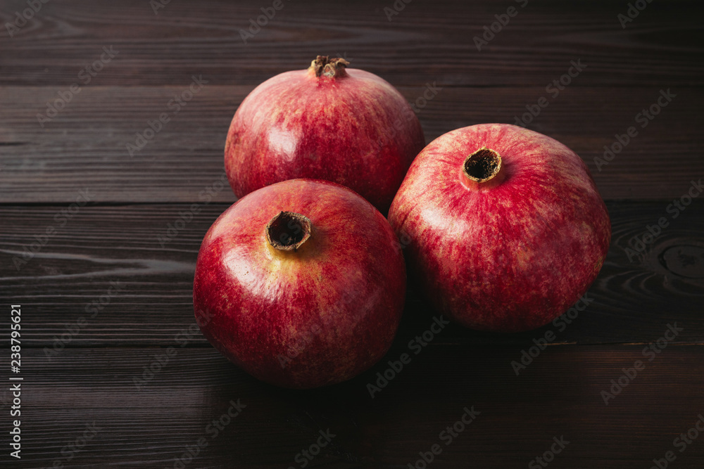 Group of pomegranate red fruits on the dark wooden background Group of pomegranate red fruits on the dark wooden background
