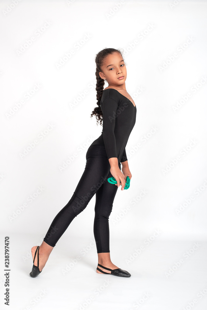 Foto de Studio shot of attractive little gymnast girl of wearing black  leggings and a bathing suit with a green jump rope on a white background,  full length. do Stock