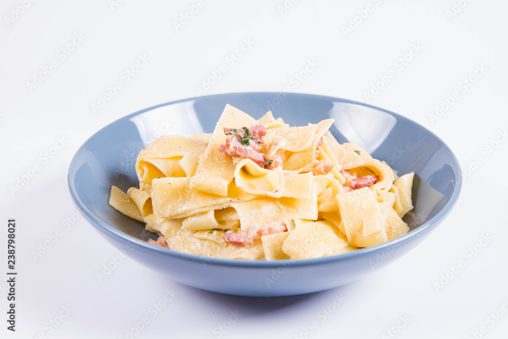 Pappardelle Carbonara on a blue plate on a white background Pappardelle Carbonara on a blue plate on a white background