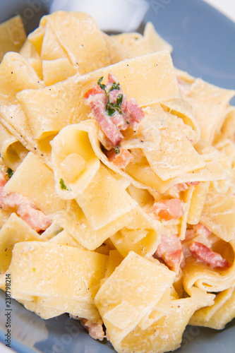 Pappardelle Carbonara on a blue plate on a white background