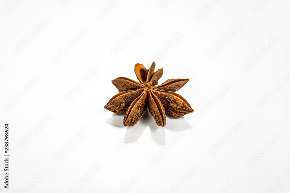 Single anise star isolated on white reflective surface Single anise star isolated on white reflective surface
