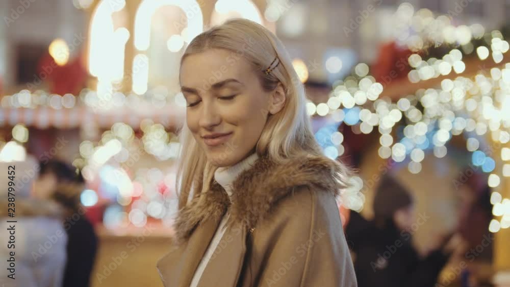 Portrait of young smiling woman at christmas market in a city. Happy attractive woman in a christmas market at night. Beautiful bokeh lights background. Portrait of young smiling woman at christmas market in a city. Happy attractive woman in a christmas market at night. Beautiful bokeh lights background.
