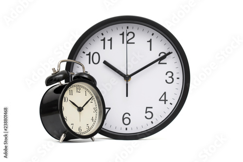 Black vintage alarm clock on the background of modern office hours. Black alarm clock and office clock on a white background. Business concept