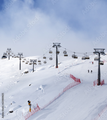 Snowy ski slope and ski-lift at sunny winter evening