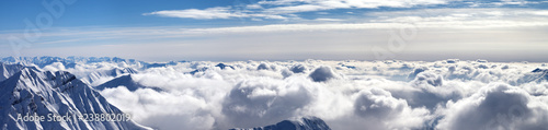 Panorama of snowy mountains covered with sunlight clouds at winter