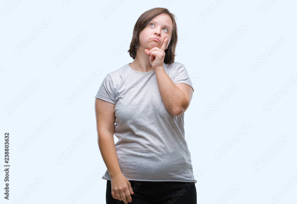 Young adult woman with down syndrome over isolated background with hand on chin thinking about question, pensive expression. Smiling with thoughtful face. Doubt concept. Young adult woman with down syndrome over isolated background with hand on chin thinking about question, pensive expression. Smiling with thoughtful face. Doubt concept.