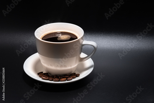 White cup and saucer with coffee on a black background