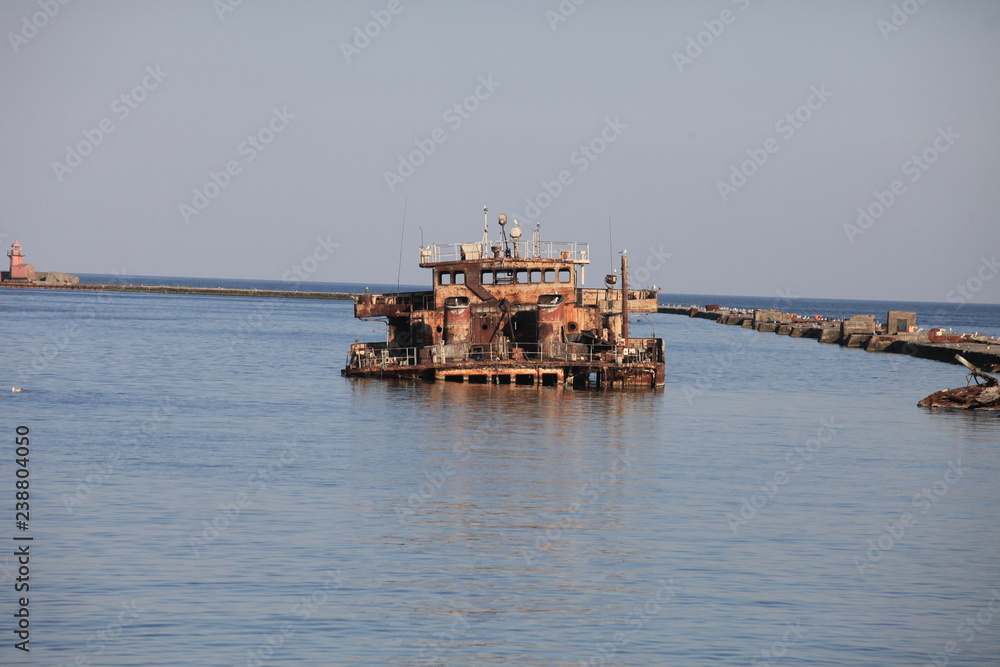 Rusty sunken barge in seaport