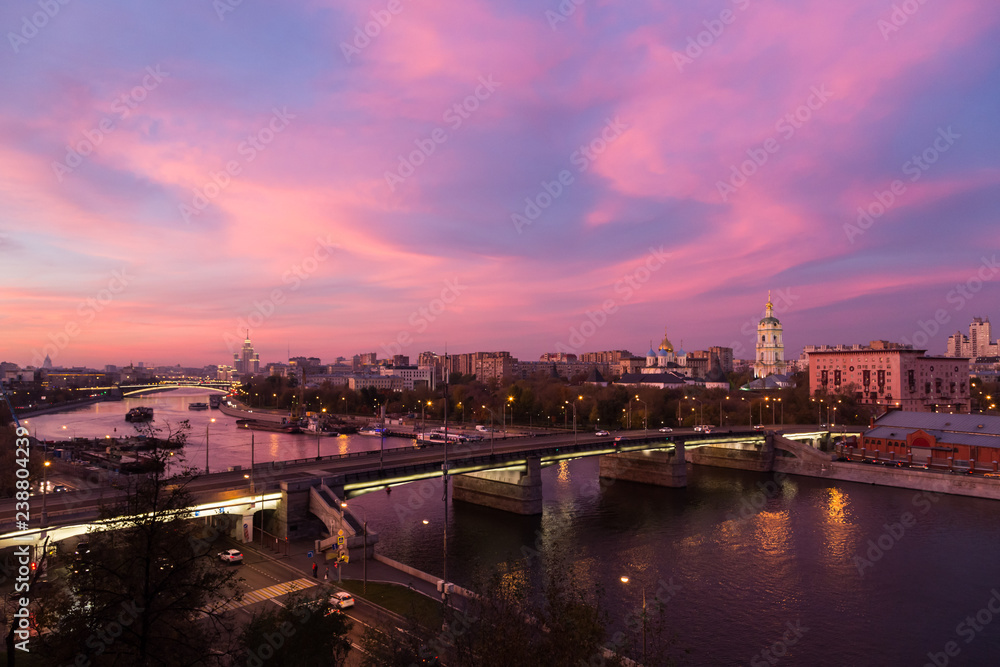 Evening, twilight and night view, red sunset over Moskva river and red skies, Novospassky Monastery (New monastery of the Saviour; the New Saviour) and Novospasskiy Bridge in Moscow, Russia.