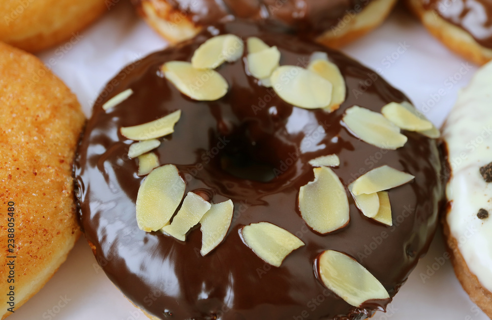 Closed up mouthwatering chocolate glazed doughnut topped with sliced almond Closed up mouthwatering chocolate glazed doughnut topped with sliced almond