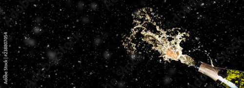 Celebration theme with splashing champagne on black background with snow and free space. Christmas or New Year, Valentines day background.