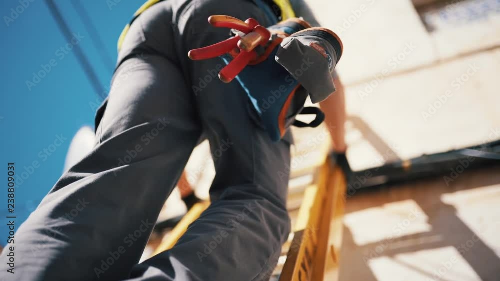 Workman Wearing High Visibility Clothing and Tool Belt Climbing a Ladder - Slow Motion Close-Up