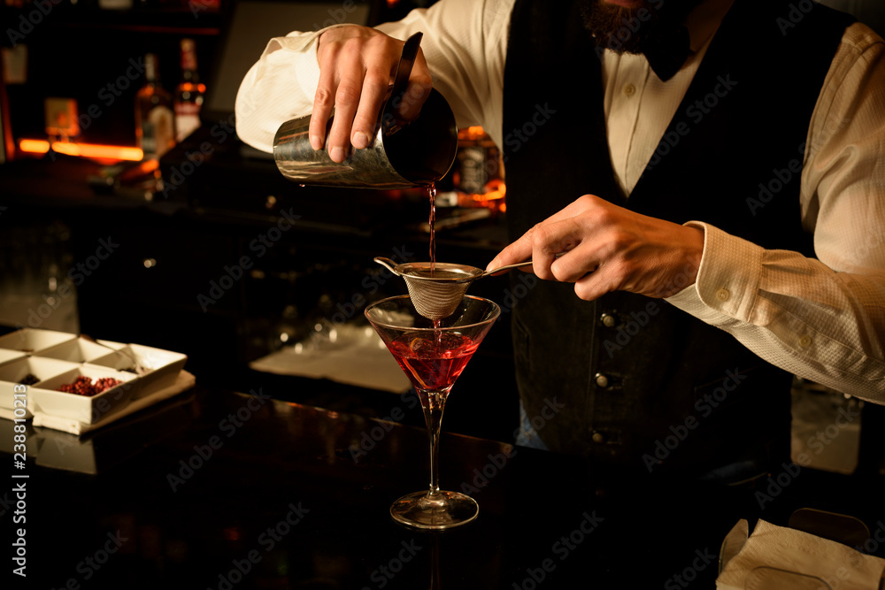 Young bartender preparing a delicious cocktail at the bar of a cocktail bar.