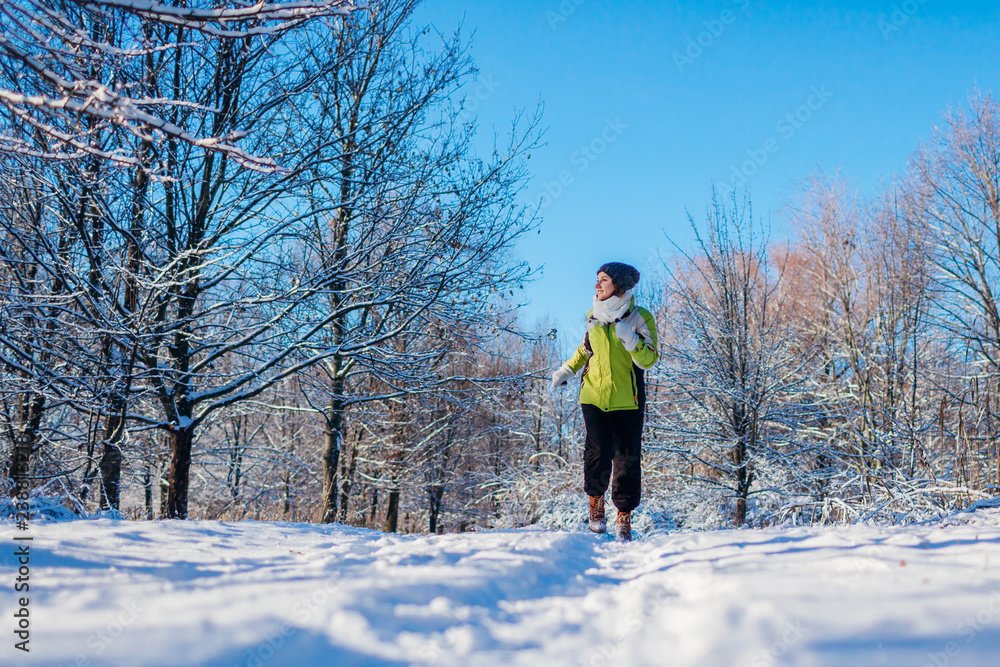 Running athlete woman sprinting in winter forest. Training outside in cold snowy weather.