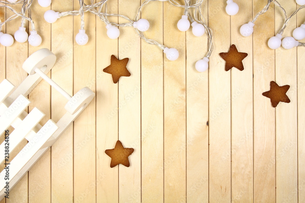 Fototapeta premium Świąteczna dekoracja - Xmas - białe sanki, lamki i pierniki na drewnianym blacie