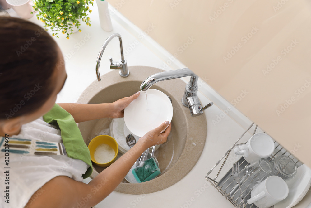 Woman washing dirty dishes in kitchen sink. Cleaning chores Woman washing dirty dishes in kitchen sink. Cleaning chores