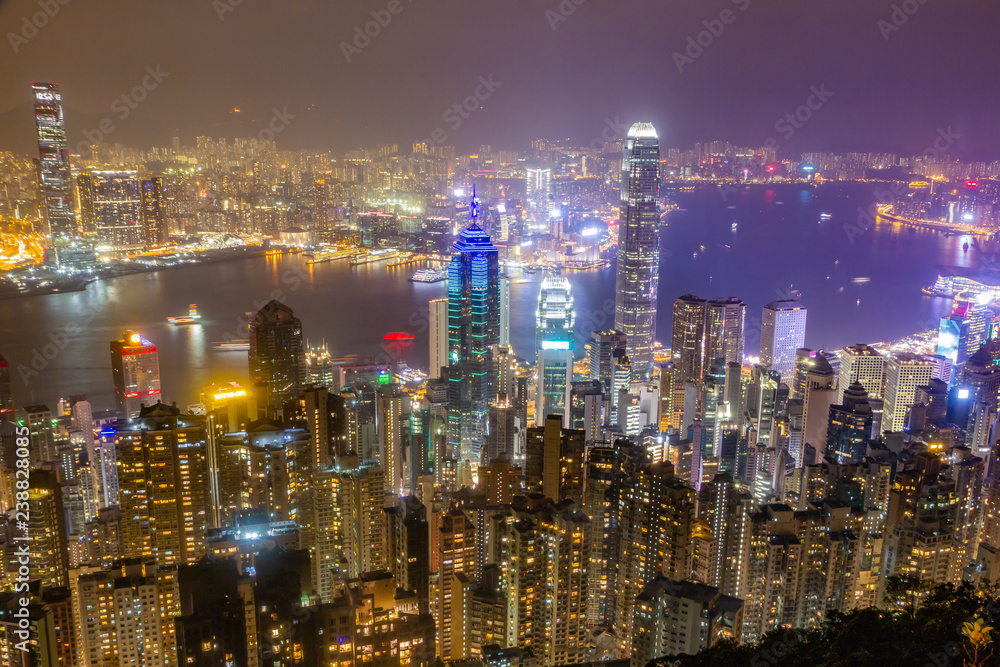 Hong Kong skyline at night as seen from Victoria Peak. Illuminated skyscrapers in foreground, Hong Kong harbor in background. Hong Kong skyline at night as seen from Victoria Peak. Illuminated skyscrapers in foreground, Hong Kong harbor in background.