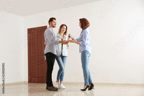 Real estate agent with young couple in new apartment
