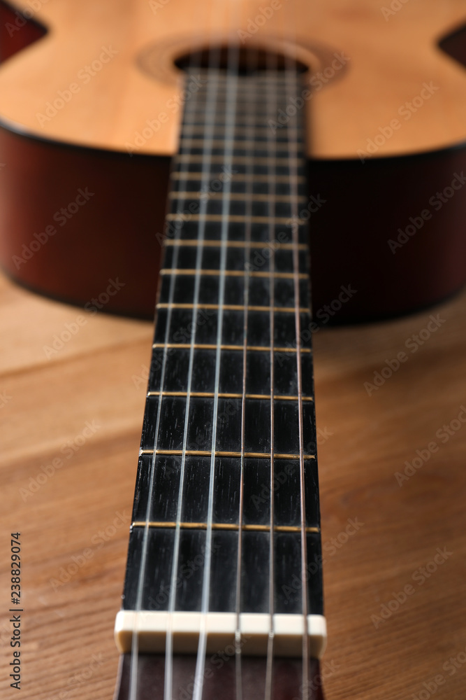 Beautiful classical guitar on wooden background, neck with strings in focus