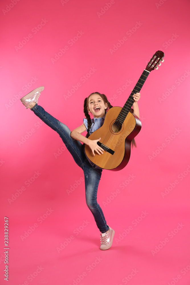 Obraz premium Cute little girl playing guitar on color background