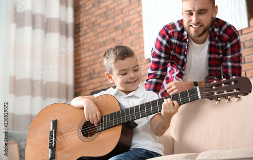 Father watching his son playing guitar at home