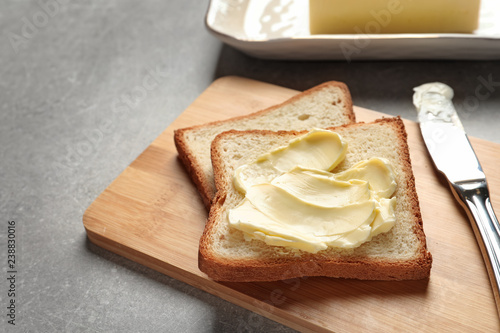Tasty bread with butter and knife on wooden board