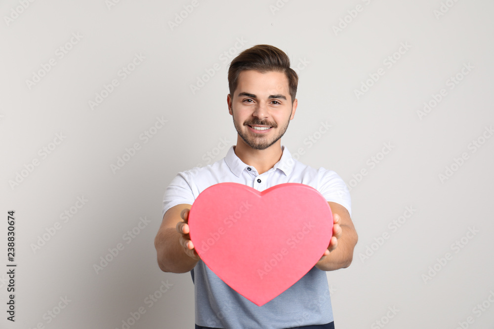 Portrait of young man with decorative heart on light background Portrait of young man with decorative heart on light background