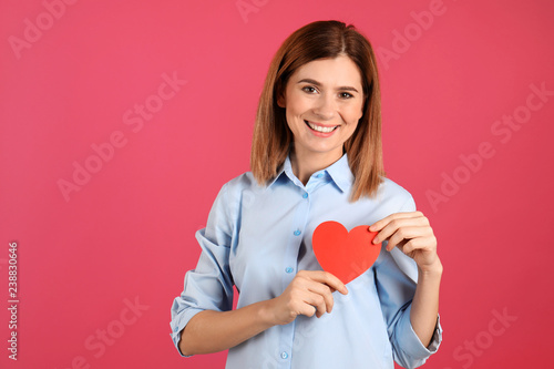 Portrait of woman with paper heart on color background. Space for text