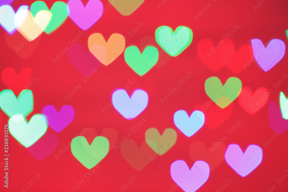 Blurred view of beautiful heart shaped lights on color background