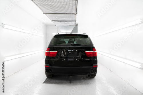 Black car in white paint booth